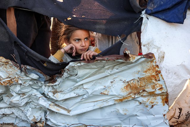 A girl watches as people inspect the site of reported Israeli bombardment on tents sheltering Palestinians displaced from Beit Lahia at a camp in Khan Yunis in the southern Gaza Strip on December 25, 2024 amid the ongoing war in the Palestinian territory between Israel and Hamas. (Photo by Bashar Taleb/AFP Photo)