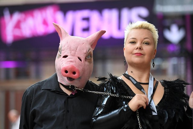 A woman leads a pal wearing a pig's mask at the annual Venus erotic trade fair in Berlin, Germany on 12 October 2017. (Photo by Alamy Live News)