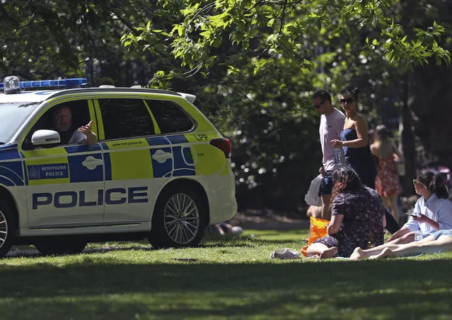 Police officers in a patrol car move sunbathers on in Greenwich Park, as the UK continues its lockdown to help curb the spread of coronavirus, in London, Saturday May 9, 2020. (Photo by Yui Mok/PA Wire via AP Photo)