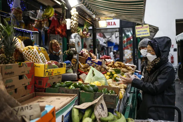 People shop in a covered market in downtown Rome Friday, April 17, 2020. Covered markets were among the activities that were allowed to continue working open during the coronavirus outbreak in Italy. (Photo by Cecilia Fabiano/LaPresse via AP Photo)