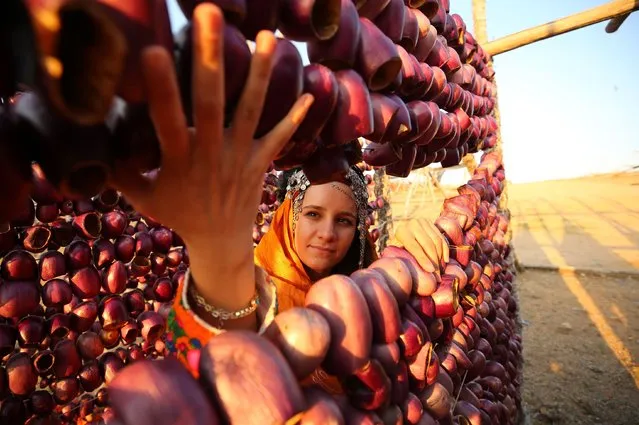 A girl is seen as vegetables brought to the high hills of the city to be dried are stringed by the workers one by one with the help of needles and hung in the exhibition areas specially made of wood in Gaziantep, Turkiye on August 02, 2022. (Photo by Mehmet Akif Parlak/Anadolu Agency via Getty Images)