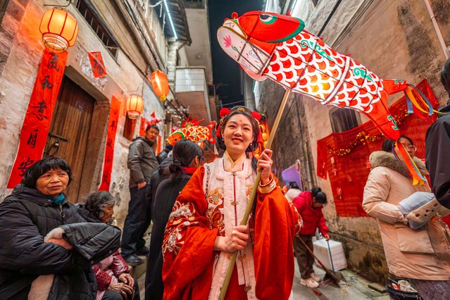 A tourist poses with a fish-shaped lantern on the sixth day of the Spring Festival, or the Chinese New Year, on February 3, 2025 in Shexian County, Huangshan City, Anhui Province of China. A festive atmosphere has permeated across China as various celebrations are taking place across the country to mark the Chinese New Year or Spring Festival. (Photo by Fang Jianzhong/VCG via Getty Images)