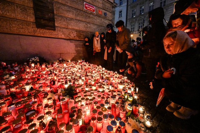 People place candles and flowers at a makeshift memorial for the the victims of the Charles University's shooting, outside the Charles University in central Prague, on December 23, 2023, during a national mourning day. Flags on public buildings flew at half mast December 23, 2023 and masses were scheduled across the Czech Republic for a day of national mourning after a deadly shooting at Prague's Charles University – the worst in the country in decades A 24-year-old student opened fire at the Faculty of Arts on December 21, 2023, killing 13 people and then himself. Another person died in hospital later on. (Photo by Michal Cizek/AFP Photo)