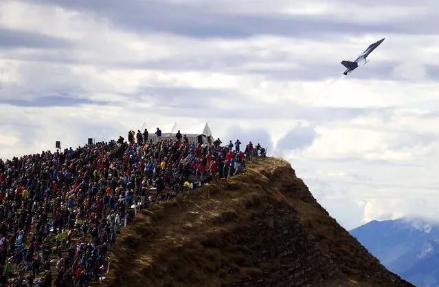 Members of the public watch a Swiss military fighter jet perform during an airshow in Axalp, near Meiringen in the canton of Bern, Switzerland, on October 11, 2012. (Photo by Peter Klaunzer/Keystone)