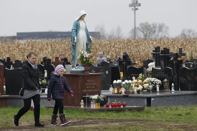 People visit a cemetery in Lomna near Warsaw, Poland, Wednesday, November 1, 2017. Candles and flowers cover tombstones in graveyards across Poland  on All Saints' Day. (Photo by Czarek Sokolowski/AP Photo)