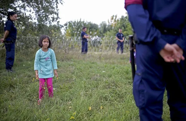 A migrant girl looks on as she is guarded by Hungarian police after being detained for illegal crossing from Serbia to Hungary near the village of Asotthalom, September 16, 2015. (Photo by Dado Ruvic/Reuters)