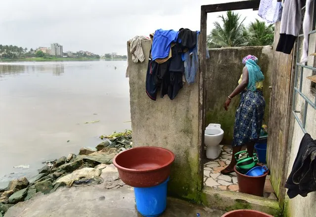 A woman cleans a toilet in an impoverished neighbourhood near a lagoon in Abidjan, Ivory Coast on November 14, 2017. (Photo by Issouf Sanogo/AFP Photo)