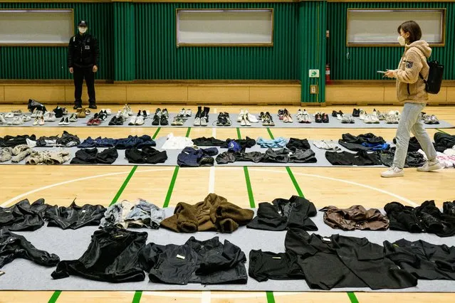 A journalist (R) walks amongst personal belongings retrieved by police from the scene of a fatal Halloween crowd surge that killed more than 150 people in the Itaewon district are displayed at a gymnasium for relatives of victims to collect, in Seoul on November 1, 2022. At least 156 mostly young people were killed, and scores more injured, in a deadly crowd surge late October 29 at the first post-pandemic Halloween party in Seoul's popular Itaewon nightlife district. (Photo by Anthony Wallace/AFP Photo)