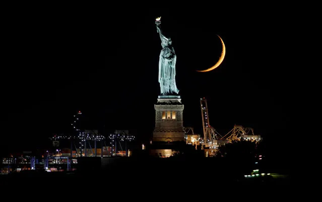An 8 percent illuminated crescent moon sets behind the Statue of Liberty on October 27, 2022, in New York City. (Photo by Gary Hershorn/Getty Images)