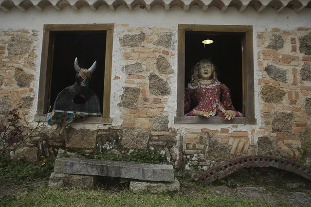 In this November 10, 2017 photo, traditional Maricota characters “Boi de Mamao” right, and the ox, left, peer from the windows at the Cultural Center during preparations for the Azorean Culture Festival which celebrates the culture of the Azores, the Portuguese island chain that lies in the mid-Atlantic, in Enseada de Brito, in Brazil's Santa Catarina southern state. In the mid-18th century, several families from the mid-Atlantic archipelago migrated to settle here, and the festival reflects the resulting mix of Azorean culture and the native and African traditions in Brazil. (Photo by Eraldo Peres/AP Photo)