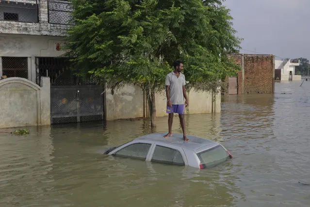 An Indian man, stands on his car that got submerged in flood waters as he waits for a boat next to his house in Allahabad, Uttar Pradesh state, India, Saturday, Aug. 27, 2016. Flood water levels stabilized with rains ebbing over the past four days in this northern state, where 200,000 people had moved to relief centers after their homes were submerged. (Photo by Rajesh Kumar Singh/AP Photo)