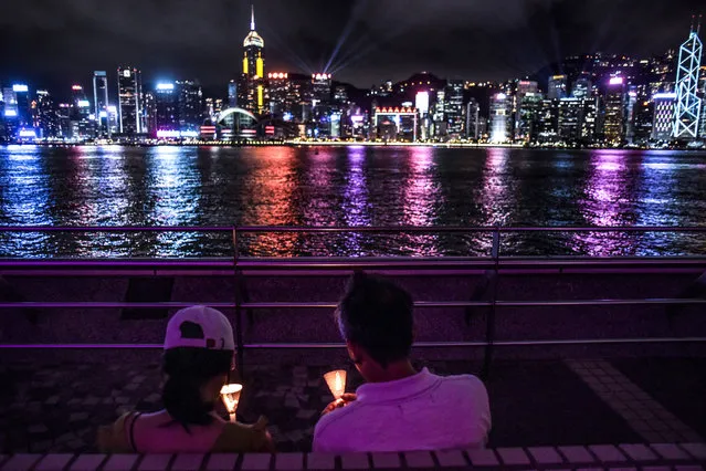 A couple hold candles along the Tsim Sha Tsui waterfront in Hong Kong on June 4, 2020, to mark the 31st anniversary of the 1989 Tiananmen Square crackdown in Beijing. Tens of thousands of people across Hong Kong lit candles and chanted democracy slogans on June 4 to commemorate China's deadly Tiananmen crackdown, defying a ban against gathering as tensions seethed over a planned new security law. (Photo by Richard A. Brooks/AFP Photo)