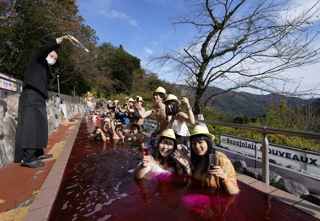 A sommelier empties a bottle of 2022 Beaujolais Nouveau wine as people bathe in a red colored hot water bath, on the day of the Beaujolais Nouveau official release, at Hakone Kowakien Yunessun hot spring resort in Hakone, Japan, 17 November 2022. Japan is a major market for the Beaujolais Nouveau. However, prices have largely increased from the previous year due to high air freight costs and a weak yen. (Photo by Franck Robichon/EPA/EFE)
