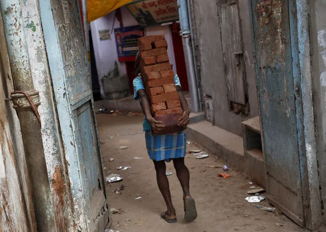 A labourer carries bricks on his back through an alley in the old quarters of Delhi, September 3, 2013. (Photo by Anindito Mukherjee/Reuters)