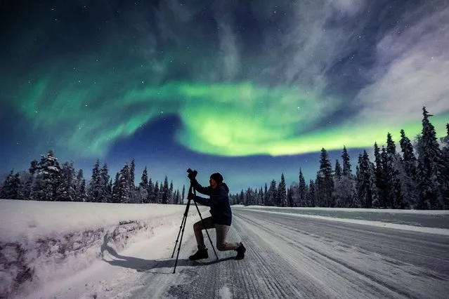 A photographer takes pictures as an aurora is seen in the sky in Pajala, Sweden on February 10, 2022. (Photo by Alexander Kuznetsov/Reuters)