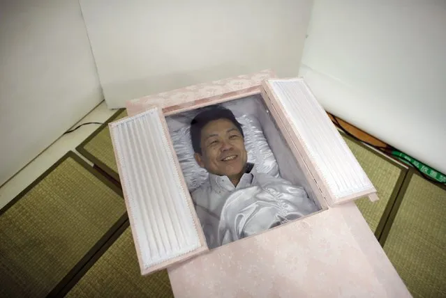 Kazuhiko Kitano smiles as he lies in a coffin during an end-of-life seminar held by Japan's largest retailer Aeon Co in Tokyo October 24, 2014. (Photo by Toru Hanai/Reuters)