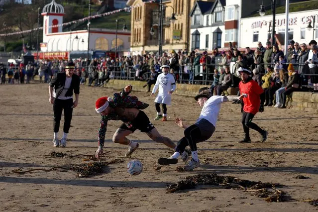 Participants vie for the ball in the Fishermen & Firemen's Boxing Day football match, a major fundraiser for the Fishermen and Firemen's Charity which provides help for the elderly and the infirm during the winter months, on the South Bay Beach in Scarborough, Britain on December 26, 2022. The match is believed to be Scarborough's oldest surviving custom, played on the Boxing Day since 1898. (Photo by Lee Smith/Reuters)