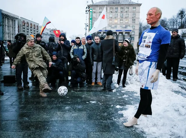 Ukrainian serviceman kicks a ball at a mannequin of Russian President Vladimir Putin dressed in a football outfit as he takes part in a performance during a rally against Russia's hosting of the soccer World Cup this year due to its actions against Ukraine, in Kiev, Ukraine January 22, 2018. (Photo by Gleb Garanich/Reuters)