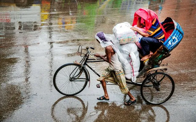A rickshaw puller pulls his rickshaw with a passenger covering himself with plastic during the rain in Dhaka, Bangladesh, 22 August 2020. The summer monsoon season in Bangladesh is witnessed from June through mid-October. (Photo by Monirul Alam/EPA/EFE/Rex Features/Shutterstock)