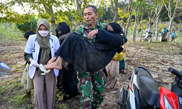 A soldier helps a Rohingya refugee following her arrival by boat in Lamnga beach, Aceh province on January 8, 2023. (Photo by Chaideer Mahyuddin/AFP Photo)