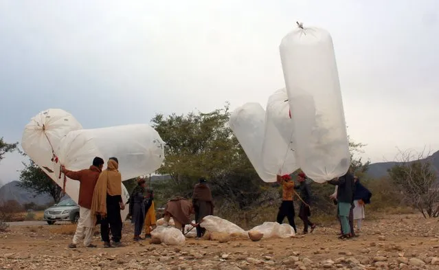 Local residents fill up plastic bags with natural gas to be used for cooking food at home, in Karak district in the Khyber Pakhtunkhwa province, known for its rich resources of natural gas and oil, Karak, Pakistan, 18 January 2023. The government has not established any proper infrastructure for providing natural gas to local residents or surrounding areas in Karak district, Khyber Pakhtunkhwa, so people are putting their lives at risk just to use natural gas as a means of cooking their food at home. People have been using a hose to extract gas from main supply lines instead of drilling. The gas was then transported from the field for home-use using plastic bags filled with helium balloons. Special Assistant to Chief Minister on Information, Barrister Mohammad Ali Saif has said that a crackdown against those involved in gas storage in plastic shopping bags from gas pipelines in Karak is in progress. (Photo by Basit Gilani/EPA/EFE)