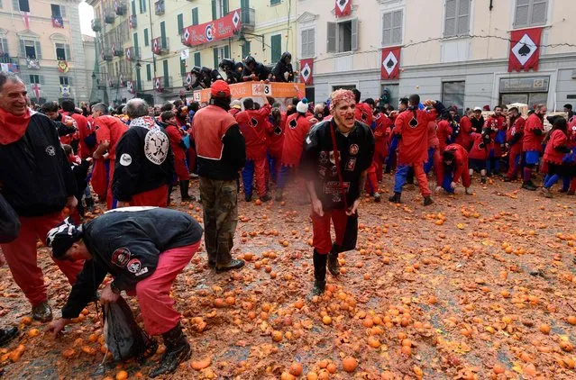 Participants throw oranges from a float during the traditional “Oranges battle” of Ivrea Carnival, near Turin, on February 11, 2018. Established in 1808, the Carnival of Ivrea is one of the oldest and most particular festivals in the world. It is the Battle of the Oranges that reevokes the civil war that broke out between the people of Ivrea and the Royal Napoleonic Troops. The battle is made up of squads of aranceri or orange throwers on foot (representing the people) and defending their piazzas from those throwing the oranges (that represent arrows) from carts (representing the Napoleonic troops). (Photo by Miguel Medina/AFP Photo)