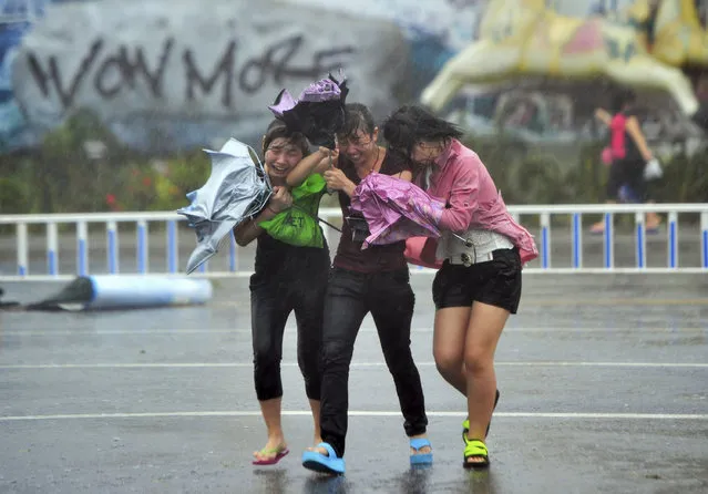 People cross a street against strong wind and heavy rain under the influence of Typhoon Haiyan, in China's Hainan province, November 2013. (Photo by Reuters/China Daily)