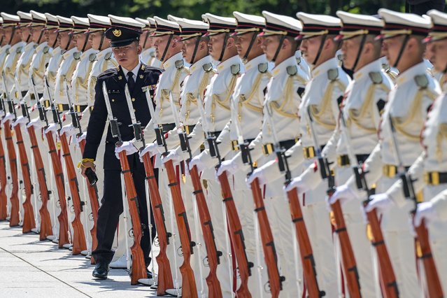 A senior member (L) checks an honour guard standing in formation before the arrival of Japan's Prime Minister Shigeru Ishiba for a visit to the Ministry of Defence in central Tokyo on June 30, 2025. (Photo by Richard A. Brooks/AFP Photo)