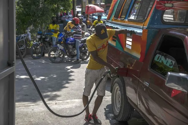 A man fills his tank at a gas station in Port-au-Prince, Haiti, Saturday, November 12, 2022. Whoops of excitement echoed through the streets of Port-au-Prince early Saturday as gas stations opened across Haiti for the first time in two months after a powerful gang lifted a crippling fuel blockade. (Photo by Joseph Odelyn/AP Photo)