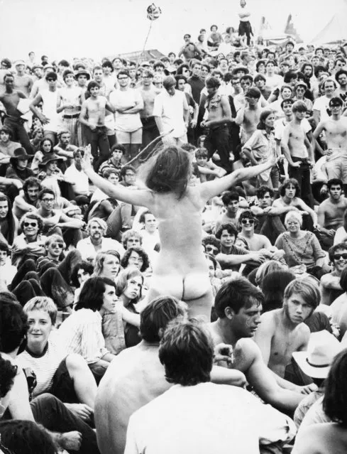 A naked young woman stands up amidst the crowd during the Woodstock Festival at White Lake, Bethel, New York, August 1969. (Photo by Archive Photos/Getty Images)