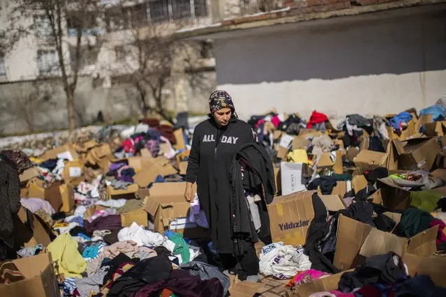 A woman who survived the earthquake checks out donated clothes in Golbasi, Turkey, Monday, February 13, 2023. Thousands left homeless by a massive earthquake that struck Turkey and Syria a week ago packed into crowded tents or lined up in the streets for hot meals Monday, while the desperate search for anyone still alive likely entered its last hours. (Photo by Francisco Seco/AP Photo)