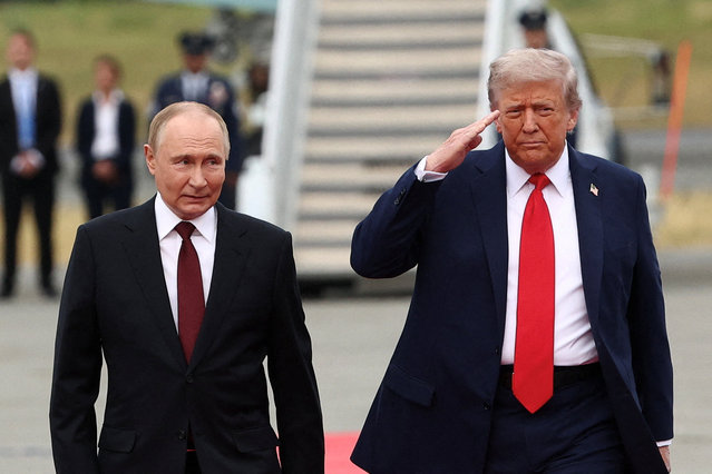 President Donald Trump salutes as he walks with Russian President Vladimir Putin at Joint Base Elmendorf-Richardson in Anchorage, Alaska, on August 15, 2025. (Photo by Kevin Lamarque/Reuters)