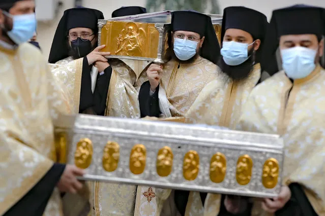 Priests, wearing masks against the COVID-19 infection, carry the remains of Saint Dimitrie Bassarabov, the patron saint of the Romanian capital, on the first of three days of pilgrimage, taking place at a much smaller scale than usual, due to the pandemic control imposed measures, in Bucharest, Romania, Sunday, October 25, 2020. Romania's daily tally of coronavirus infections rose above 5,000 for the first time last week and patients in intensive care units also reached a new high. (Photo by Vadim Ghirda/AP Photo)