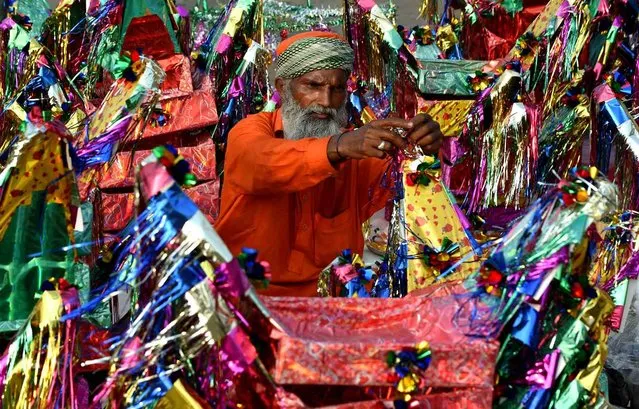 In this photograph taken on September 22, 2016, a Pakistani devotee decorates symbolic paper boats, an offering to Muslim saint Abdulqadir Jilani as a way of giving thanks after their desire to give birth to a son was fulfilled, before dropping it into the water during an annual ceremony on the banks of the River Ravi in Lahore. The ceremony commemorates a centuries-old tale that Muslim saint Abdulqadir Jilani raised a sunken ship carrying a wedding party, at the pleading of the groom's mother, saving all the occupants. (Photo by Arif Ali/AFP Photo)