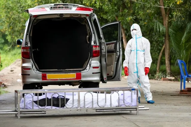 A volunteer wearing a personal protective suits prepares to bury the body of a person who died from the coronavirus at a cemetery in Yangon, Myanmar, October 17, 2020. (Photo by Shwe Paw Mya Tin/Reuters)