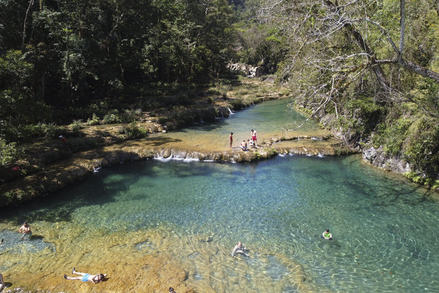 In this aerial view tourists swim in Semuc Champey National Park in Alta Verapaz, Guatemala on March 13, 2025. The Natural monument of Semuc Champey, which in the local Q'eqchi Maya dialect means “where the river disappears into the earth”, consists of a natural 300 meters long limestone bridge, under which the Cahabon River passes. Atop the bridge there are a series of stepped pools, ranging from turquoise to emerald-green, good for swimming. (Photo by Johan Ordonez/AFP Photo)