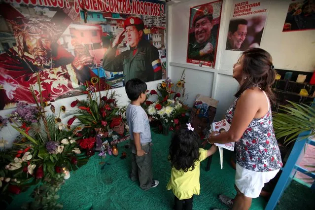 A woman and her two children visit a people's shrine built in honor of late Venezuela's President Hugo Chavez at the “23 de Enero” or “23rd of January” slum in Caracas, Venezuela, Wednesday, April 3, 2013. The shrine, named  “Saint Hugo Chavez del 23”, has been visited by tens of thousands of Venezuelans to pay homage to a president for some, a saint for others. (Photo by Fernando Llano/AP Photo)