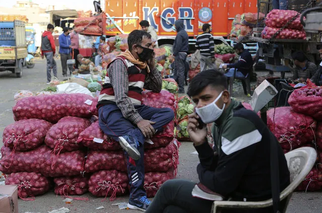 Indians wearing face masks as a precaution against the coronavirus wait for customers at a vegetable wholesale market in Jammu, India, Friday, November 6, 2020. (Photo by Channi Anand/AP Photo)