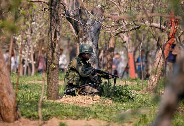 An Indian army soldier takes his position in an orchard near the site of a gunbattle with suspected militants at Kachdoora village in south Kashmir's Shopian district April 1, 2018. (Photo by Danish Ismail/Reuters)