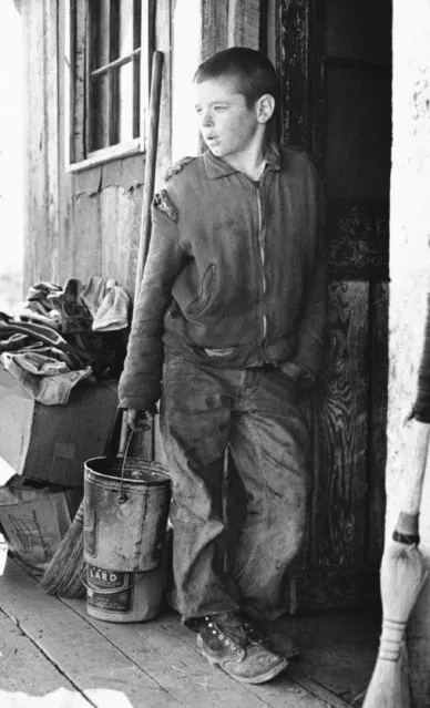 Shabbily-dressed Isaac Grady Sanders, 13, leans against door of shack in Whitwell, Tenn., December 16, 1963 where his family will have a stark and bleak Christmas. His father is one of thousands of Former coal miners who were laid off several years ago. The lad, oldest of seven children, lives with his grandmother across the road from his parents' home. The rest of the family three girls and three boys and their parents live and sleep in a 12-by-12 room, furnished with two double beds, a couch and a stack of blankets. (Photo by AP Photo)