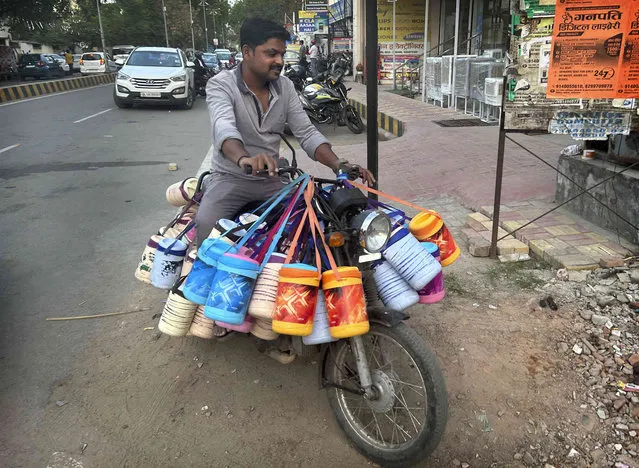 A person delivery food tiffins or lunch boxes to students and office goers, in Prayagraj, India, Monday, April 10, 2023. (Photo by Rajesh Kumar Singh/AP Photo)