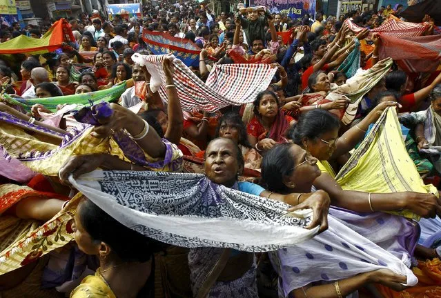 Hindu devotees hold up scarves to receive rice as offerings being distributed by the temple authority on the occasion of the Annakut festival in Kolkata, India, November 12, 2015. Annakut is celebrated on the first day of the full moon in the Kartik month where 56 types of food items are prepared and given to the worshippers. (Photo by Rupak De Chowdhuri/Reuters)