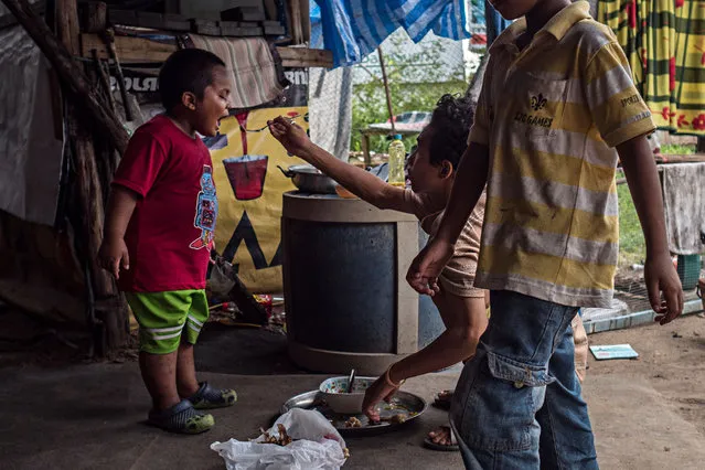 A teenager feeds a boy. Both live on the site. (Photo by Lauren DeCicca/The Guardian)