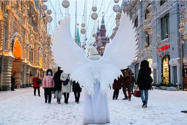 A woman in an angel costume in Nikoskaya Street in central Moscow, Russia on January 21, 2021 during a snowfall at –11°C. (Photo by Sergei Savostyanov/TASS)