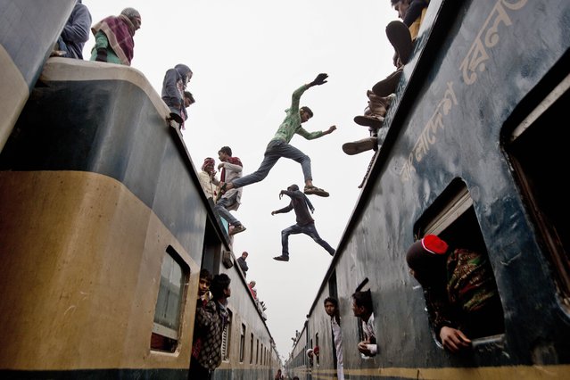Bangladeshi Muslim boys jump from the top of one overcrowded train to another as thousands of Bangladeshi Muslims try to return home after attending three-day Islamic Congregation on the banks of the River Turag in Tongi, 20 kilometers (13 miles) north of the capital Dhaka, Bangladesh, Sunday, January 11, 2015. (Photo by A. M. Ahad/AP Photo)
