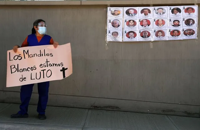 A health worker holds a sign that reads in Spanish: “The white aprons, we're in mourning” during a protest outside Petrolero Obrajes Hospital in La Paz, Bolivia, Wednesday, January 27, 2021. Health workers want Bolivia's President Luis Arce to declare a quarantine to reduce the contagion of COVID-19 that has sickened doctors and filled hospitals' intensive care units. (Photo by Juan Karita/AP Photo)
