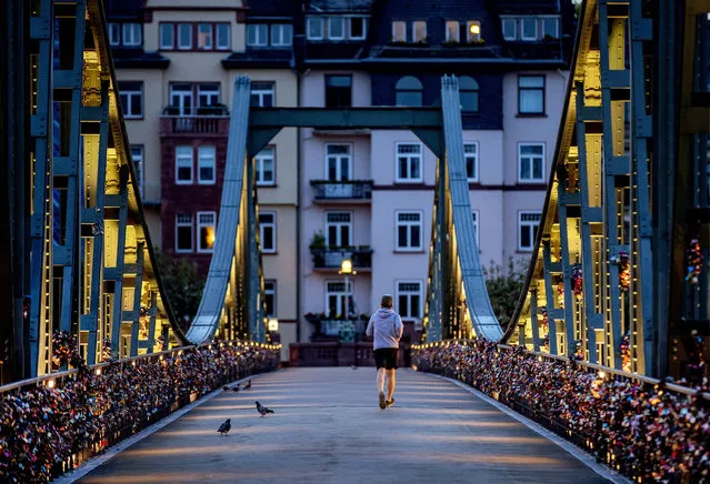 A man runs over the “Eiserner Steg” pedestrian bridge over the river Main in Frankfurt, Germany, early Monday, October 5, 2020. (Photo by Michael Probst/AP Photo)