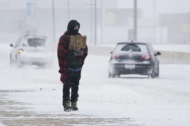 Cars drive by Michael Given as he stands at an intersection asking for money during a winter storm Sunday, February 14, 2021, in Oklahoma City. Given said he is a restaurant worker who was laid off during the coronavirus pandemic. (Photo by Sue Ogrocki/AP Photo)