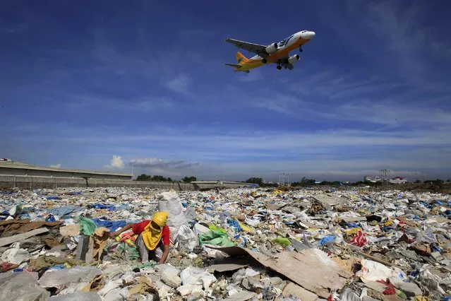 An aircraft flies overhead as a person rummages for recyclables at a garbage dumpsite in Paranaque city, metro Manila in this June 8, 2014 file photo. It could take Southeast Asia, one of the fastest growing air travel markets, two decades to set up a regulatory body to oversee safety in an industry blighted by disasters in recent years, say national regulators and airline executives. (Photo by Romeo Ranoco/Reuters)
