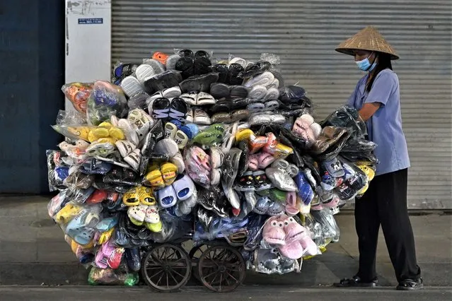 The photo taken on May 22, 2023 shows a street vendor pushing a cart of shoes and slippers in Hanoi. (Photo by Nhac Nguyen/AFP Photo)